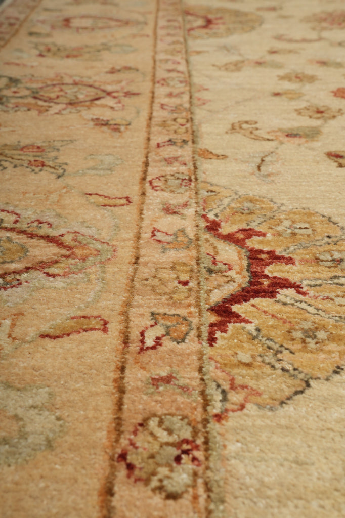 Close-up of an ornate patterned area rug with a beige and cream base and red, brown, and muted blue floral motifs.