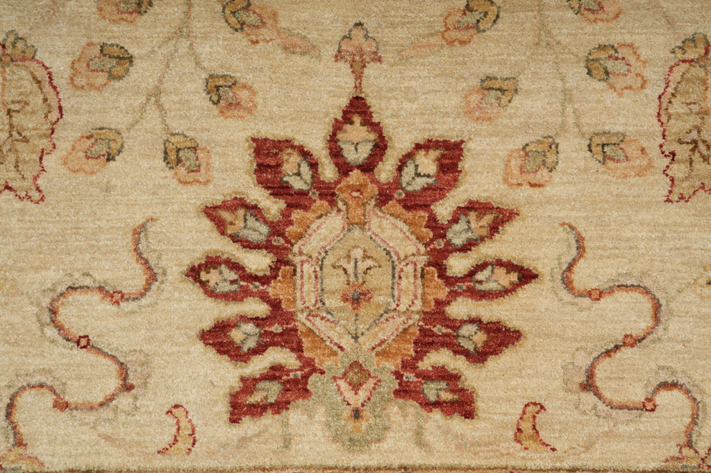 A close-up of a traditional patterned rug featuring a central medallion in rust red, terracotta, and beige, surrounded by floral motifs on a cream-colored background.