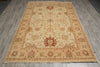 Load image into Gallery viewer, A rectangular traditional area rug with an intricate floral and medallion pattern, laid out on a gray wood-plank floor. The rug features a warm beige base with red, green, and brown accents.