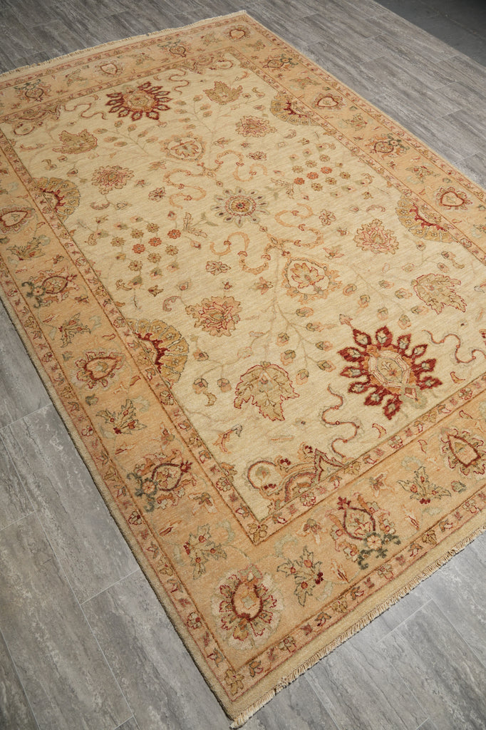 A rectangular area rug with a traditional floral and paisley pattern, shown from an angled overhead perspective on a gray wood-look floor.