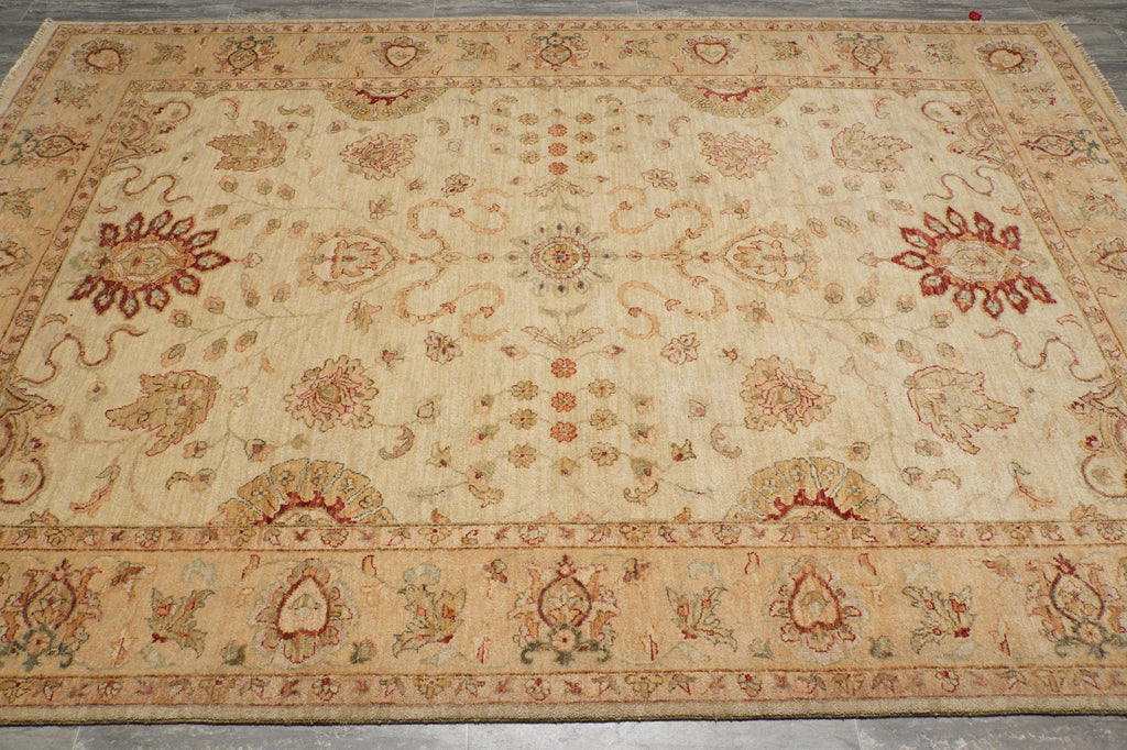 A large rectangular area rug with an intricate traditional floral and medallion pattern, featuring a warm beige base with red, green, and brown accents.