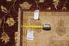Load image into Gallery viewer, A folded area rug with a floral pattern in beige, brown, and gold tones, shown with a yellow tape measure and two inventory tags on top to indicate size and condition.