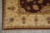 Load image into Gallery viewer, A close-up of an ornate area rug corner showing a dark brown field with floral motifs, a beige scrollwork border, and a patterned border, photographed on a gray floor.