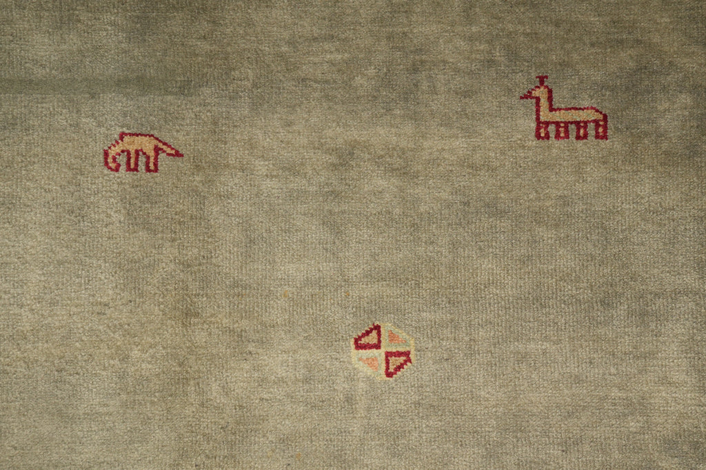 A close-up of a textured beige fabric with small red embroidered motifs, including a camel-like figure near the top right and a small geometric symbol near the bottom center.