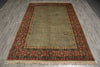 Load image into Gallery viewer, A rectangular area rug with a muted sage green center and a detailed multicolor border in red, beige, and green, shown on a gray wood-look floor.