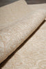 Load image into Gallery viewer, A close-up of a rolled piece of beige fabric with an intricate, raised damask or floral pattern.