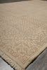 Load image into Gallery viewer, A close-up of a beige area rug with a traditional floral pattern and fringed edge, shown on a neutral gray floor.