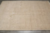 Load image into Gallery viewer, A large rectangular area rug in a light beige or cream color with an intricate, faded traditional floral pattern and a decorative border, laid out on a dark gray tiled floor.