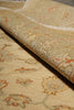 Load image into Gallery viewer, A close-up of a rolled area rug showing its detailed traditional floral pattern in beige, cream, and muted orange tones.