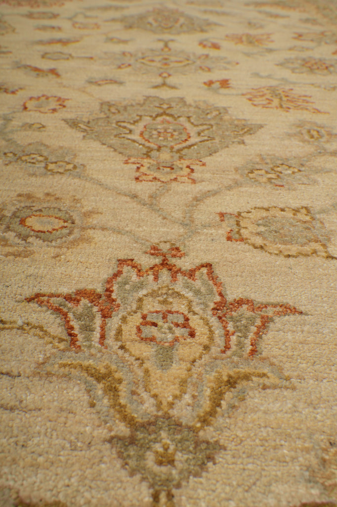 Close-up of a traditional patterned rug with beige, rust red, and gray floral motifs.