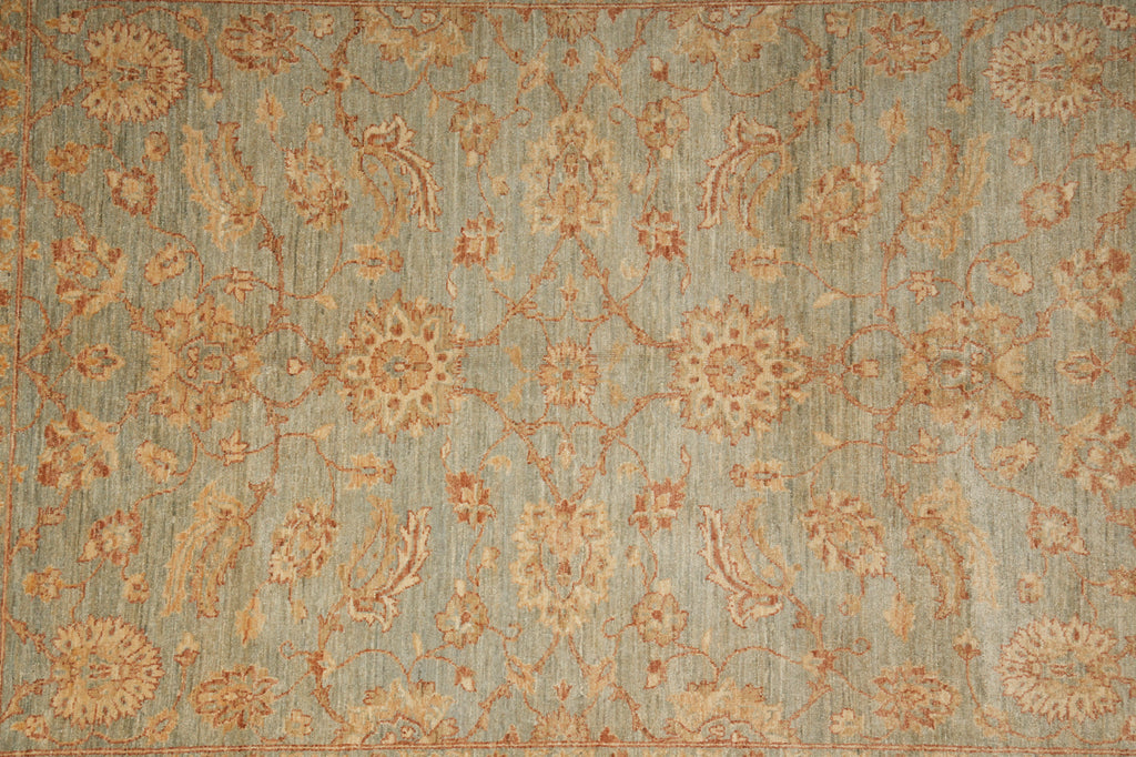 An area rug with an intricate traditional floral and paisley pattern in muted tones of sage green, beige, and terracotta orange.