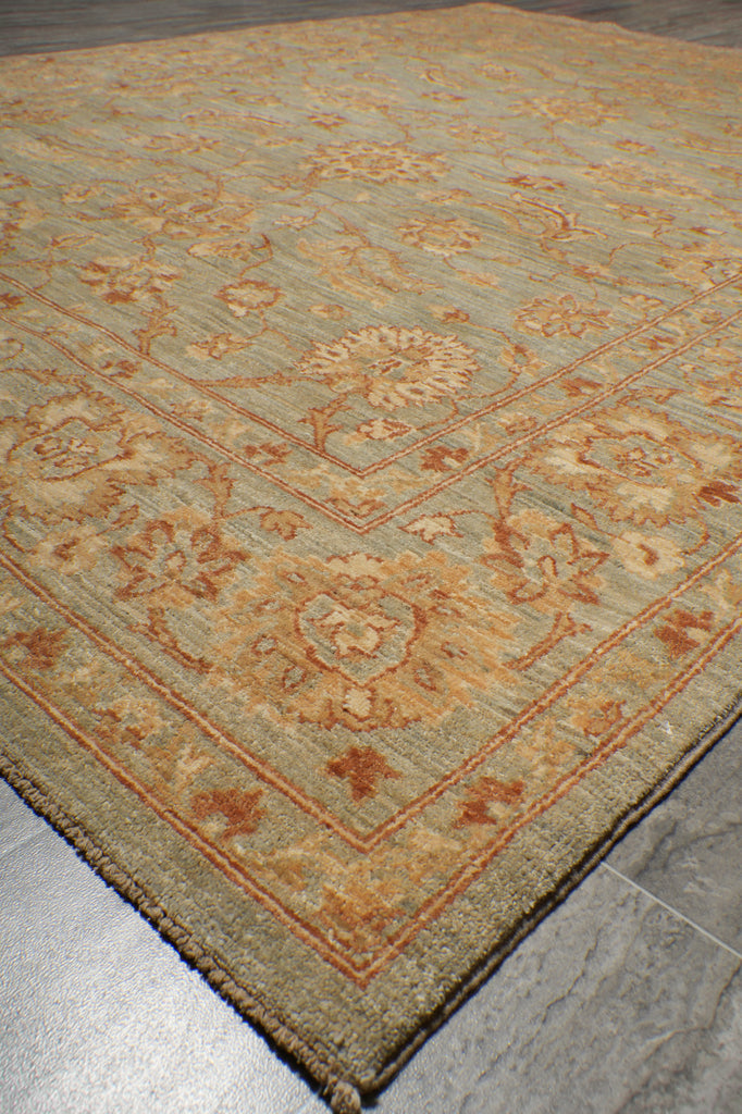A close-up of a traditional patterned area rug with a beige and light blue-gray base, decorated with warm orange and brown floral motifs.