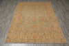 Load image into Gallery viewer, A rectangular area rug with an ornate floral and medallion pattern in muted sage green, tan, and rust orange, laid flat on a gray wood-look floor.