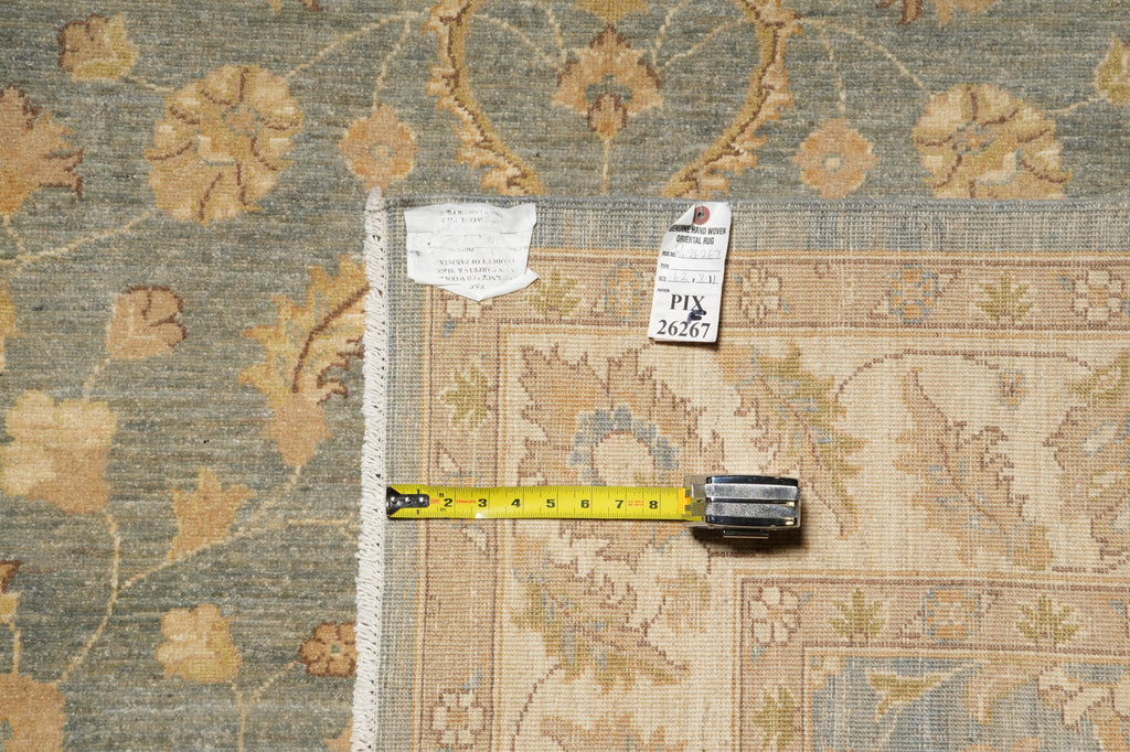 An area rug with a beige and muted blue floral pattern, shown with a yellow tape measure and tags to indicate its size and condition.