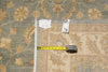 Load image into Gallery viewer, An area rug with a beige and muted blue floral pattern, shown with a yellow tape measure and tags to indicate its size and condition.