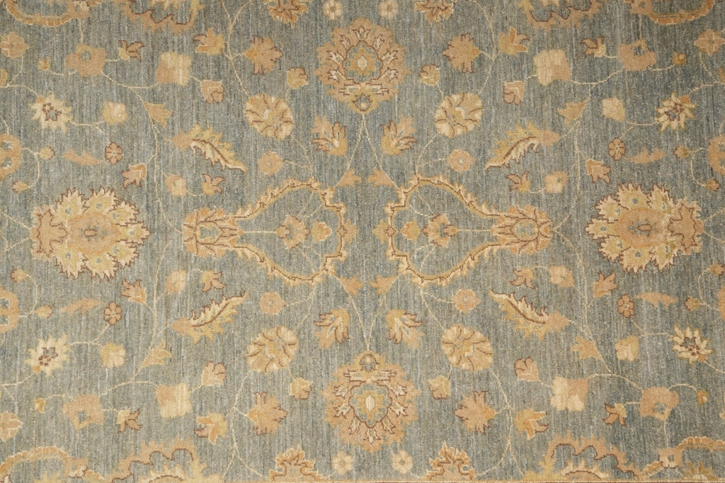 A close-up of a traditional patterned rug with a muted blue-gray background and warm beige floral motifs.