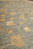 Load image into Gallery viewer, A close-up of a textured fabric or rug with a muted blue-gray base and a repeating floral pattern in tan and beige.