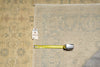 Load image into Gallery viewer, A close-up of a patterned area rug with a tape measure and price tag placed on it for scale, showing a beige and gray traditional design.