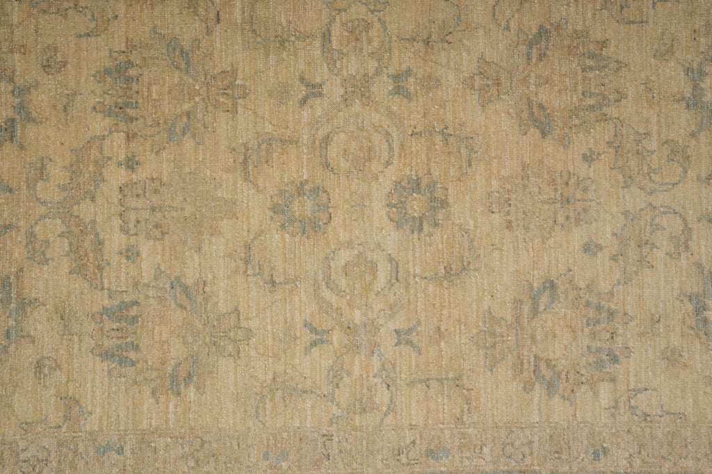 A close-up of a beige and muted blue-gray patterned rug or fabric with an ornate floral and scroll motif.