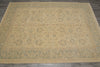 Load image into Gallery viewer, A rectangular area rug with a traditional floral pattern in beige and muted sage green, laid out on a dark gray tiled floor.