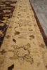 Load image into Gallery viewer, Close-up of a patterned area rug showing a beige central band with floral motifs and a dark brown border, photographed indoors on a gray floor.