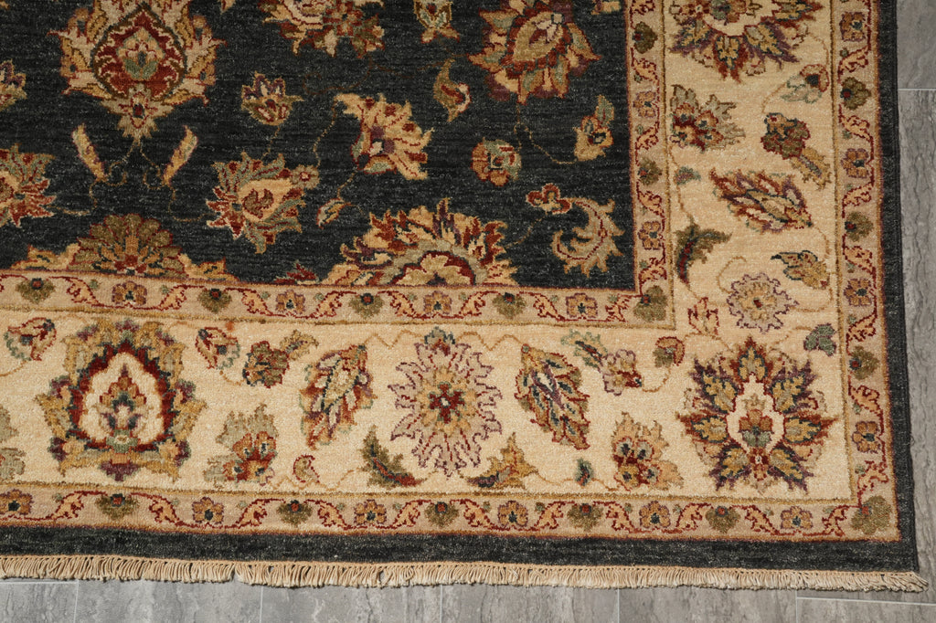 A close-up of a traditional oriental rug showing its corner, featuring a dark navy blue field, beige borders, and intricate floral motifs in red, green, and gold.