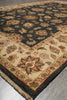 Load image into Gallery viewer, A close-up of a traditional patterned area rug shown at an angle, featuring a dark navy blue field with floral motifs, a beige inner section, and a dark border.