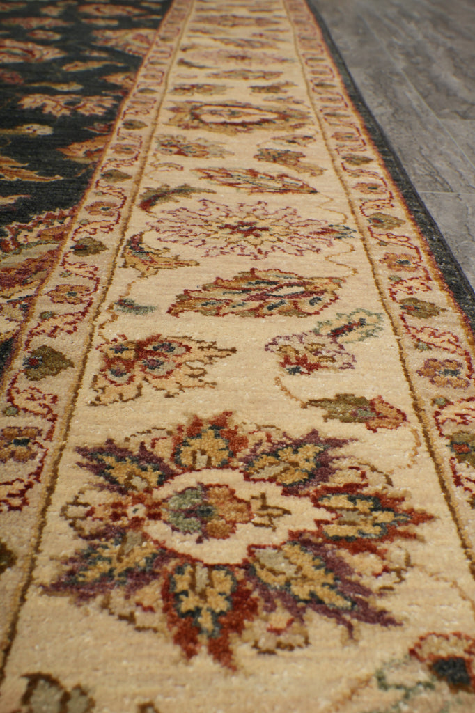 A close-up view of an ornate area rug showing its detailed floral and medallion patterns in beige, brown, red, and green tones.