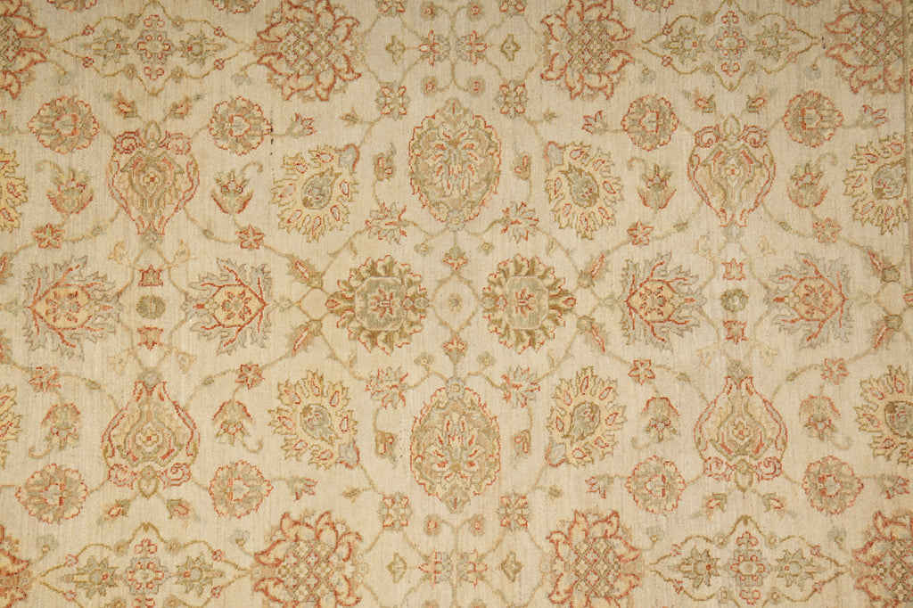 A close-up of a woven fabric or wallpaper pattern featuring ornate floral and medallion motifs in muted beige, tan, and dusty rose tones on a warm cream background.