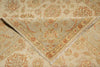 Load image into Gallery viewer, A close-up of a folded area rug with a traditional floral and medallion pattern in beige, cream, and muted rust orange tones.