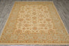Load image into Gallery viewer, A rectangular area rug with an ornate traditional floral pattern, laid out on a gray wood-look floor. The rug features a warm beige center with a border of rust orange, tan, and muted green details.