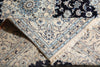 Load image into Gallery viewer, A folded traditional patterned rug with cream, navy, and light blue floral motifs and fringe trim.