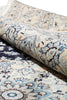 Load image into Gallery viewer, A close-up of a rolled area rug showing its detailed traditional pattern in cream, light blue, navy, and brown tones.