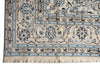 Load image into Gallery viewer, A close-up of an ornate area rug corner showing a cream base with intricate blue and dark brown floral motifs and fringed tassels.