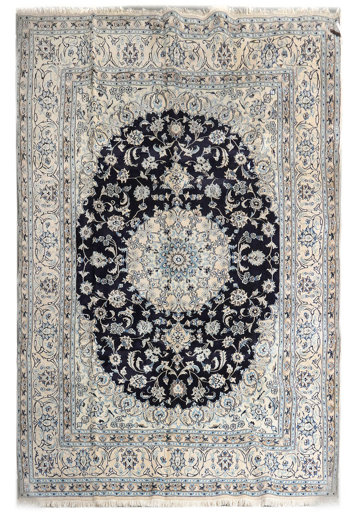 A traditional oriental area rug with a dark navy blue central medallion and intricate cream, beige, and light blue floral patterns in a rectangular field with fringed edges.