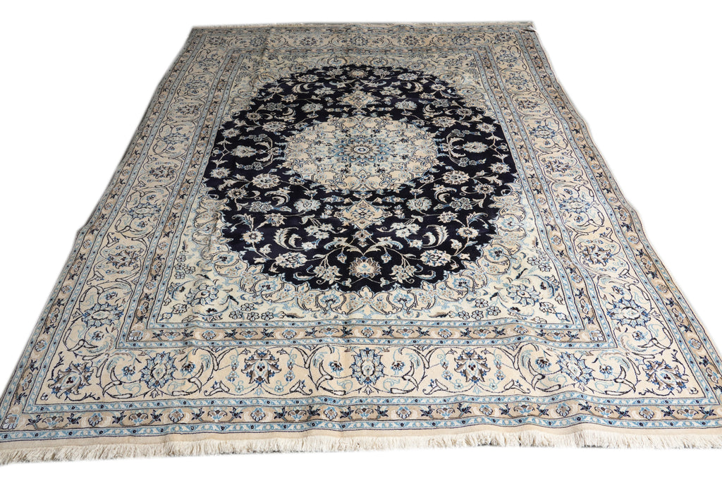 A traditional Persian-style area rug with a dark navy blue central medallion and intricate floral motifs in cream, beige, and light blue, shown flat against a white background.