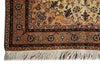 Load image into Gallery viewer, A close-up of an ornate Persian-style area rug corner, showing a cream and tan field with a detailed floral pattern, a brown and red border, and a white fringe at the bottom.