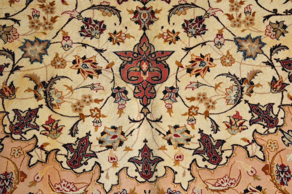 A close-up of an ornate Persian-style rug featuring a central medallion and intricate floral motifs in red, blue, green, and brown on a warm beige background.