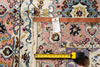 Load image into Gallery viewer, A close-up of a patterned area rug with a pink field, blue and beige motifs, and a brown leather border. A measuring tape and a product tag are placed on top of the rug to show scale and details.