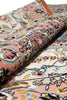 Load image into Gallery viewer, A close-up of a rolled area rug showing its detailed floral and ornamental pattern in soft pink, cream, blue, yellow, and purple tones.