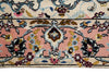 Load image into Gallery viewer, A close-up of a traditional patterned rug featuring a dusty pink field, cream borders, and a central floral medallion in blue, gold, and burgundy.