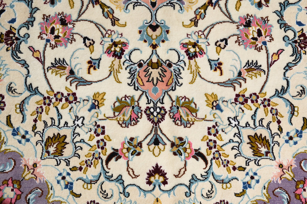 A close-up of an ornate floral patterned rug with a cream background and intricate detailing in blue, pink, gold, and purple.
