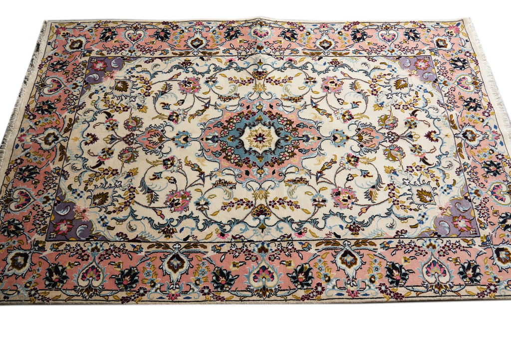 A rectangular traditional area rug with an intricate floral and medallion pattern, featuring a cream center, pink borders, and accents of blue, green, and gold.