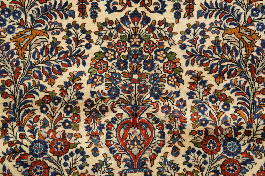 A close-up of an ornate floral patterned rug with a cream background and intricate motifs in blue, red, green, and orange.