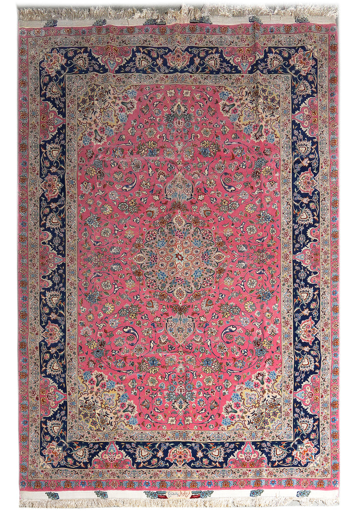 A traditional oriental area rug with a vibrant pink field, a navy blue border, and intricate floral motifs in beige, green, and blue.