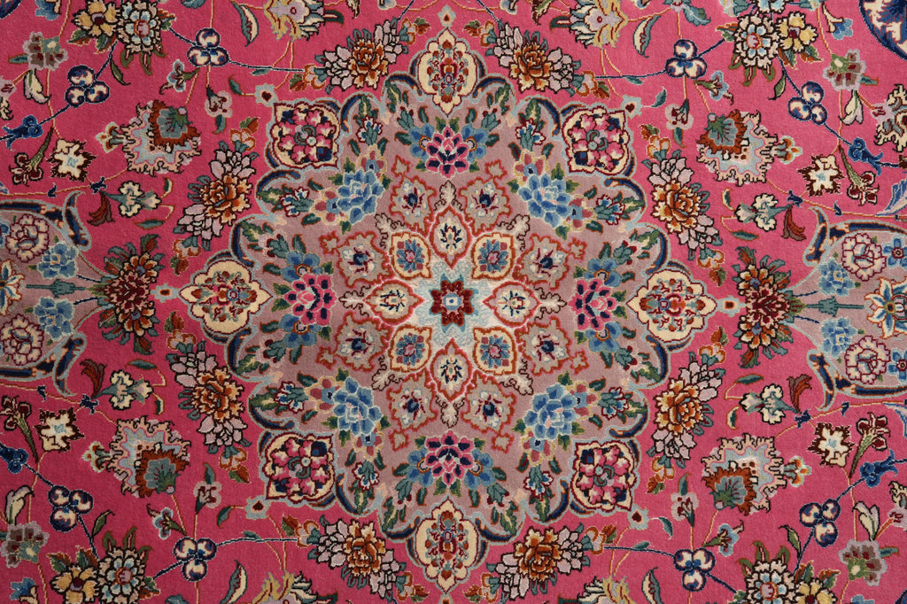 A close-up of a traditional Persian-style rug with a vibrant pink background and an intricate multicolor floral and geometric medallion pattern.