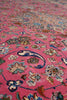 Load image into Gallery viewer, A close-up of a pink patterned rug with intricate floral and paisley motifs in blue, cream, green, and gold tones.