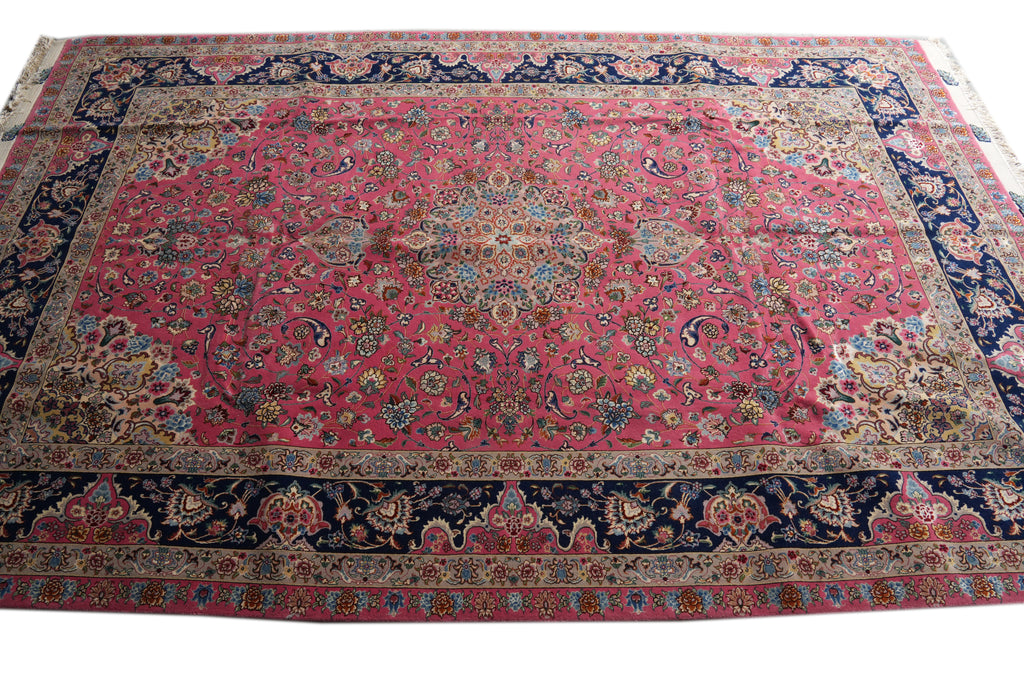 A traditional Persian-style area rug with a vibrant pink central field, intricate floral motifs, and a dark navy blue border with gold and beige accents.