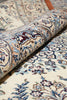 Load image into Gallery viewer, A close-up of a rolled section of an ornate patterned rug showing cream, blue, burgundy, and brown floral and paisley motifs.