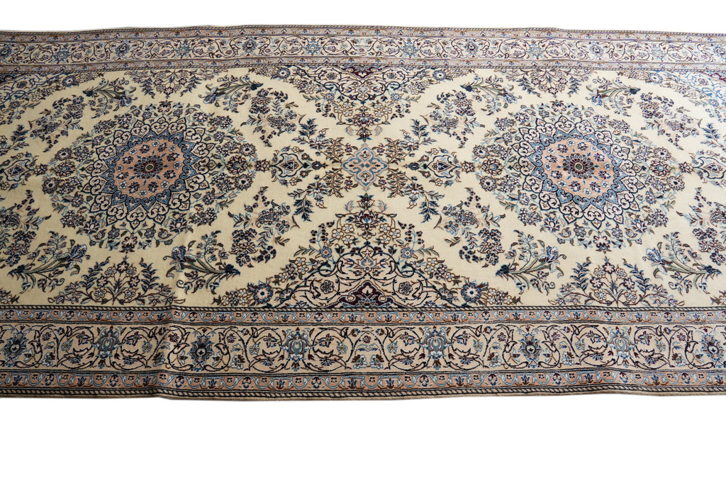 A traditional Persian-style area rug with an intricate floral pattern, featuring a cream background with blue, brown, and beige details.